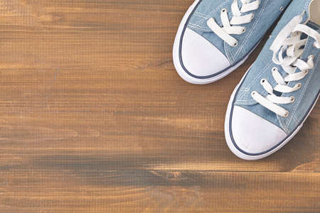 Blue sneakers on wooden background with copy space. Top view.