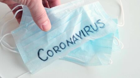 Hand put on table Mask Medical Protection with word Coronavirus. Close up.の写真素材