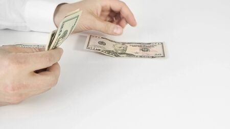 Hand of business man counting dollars bills on white tableの写真素材