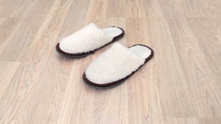 Person wears a pair of white slippers at home. Close up.