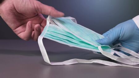 Doctor give face mask with blue medical gloves
