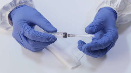 medical syringe in the hands of blue gloves