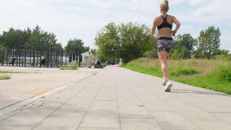 Female athletes feet running at the park. Fitness woman jogging outdoors.