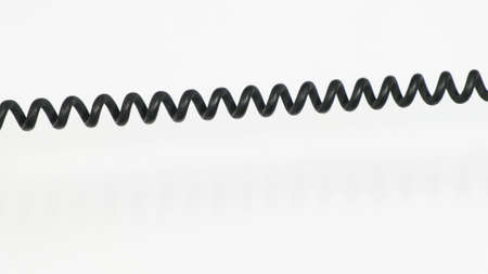 Close up of rotary phone coiled cord on white