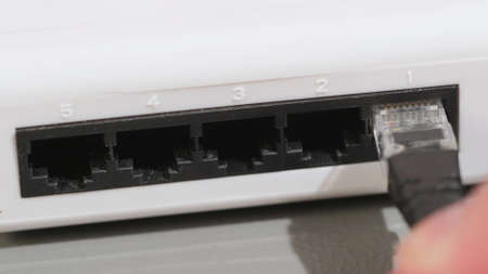 Male Hand Inserts The Blue Data Lan Cable rj45 Into Network Switch in Data Center. close upの写真素材