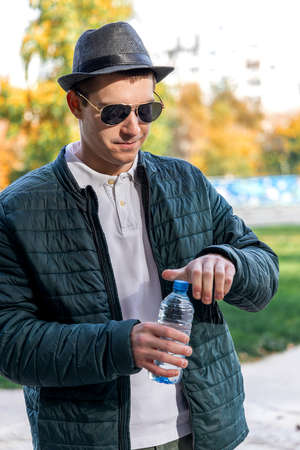 Young man in the park with the bottle up openの写真素材