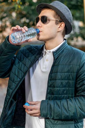 close up of a man drinking water from a bottle outsideの写真素材