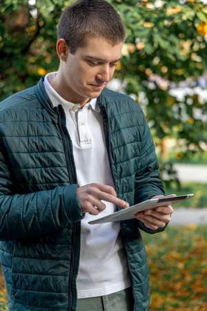 Young man surfing the internet on a tablet outdoorの写真素材