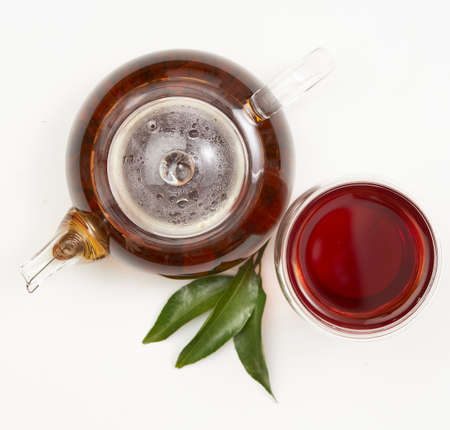 Teapot and cup of tea with green leaves on whiteの写真素材