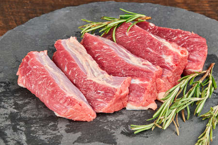 Raw beef steaks on wooden table with rosemaryの写真素材