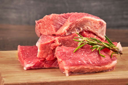 Raw beef steaks on wooden table with rosemaryの写真素材