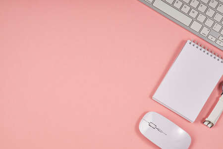 Pink office desktop. Top view table with notepad, keyboard. Mock up, copy space.の写真素材