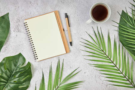 White blank note paper and big green tropical leaves on background. Flat lay. Top view. Copy space.