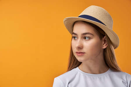 Portrait of joyful teenage girl showing, orange background with copy spaceの写真素材