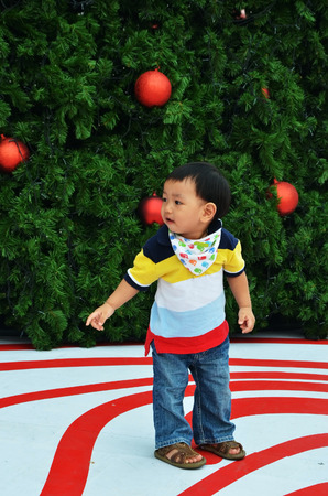 little boy stand infront of christmas treeのeditorial素材