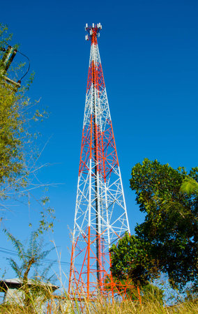 Very high red and white color mobile telecommunication post with blue skyの写真素材