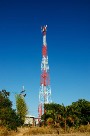 Very high red and white color mobile telecommunication post with blue skyの写真素材