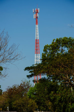 Very high red and white color mobile telecommunication post with blue skyの写真素材