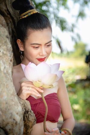 Asian woman collecting lotus flowers and she wear Traditional Thai dresses, Thailandの写真素材