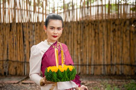 Beautiful woman ware Traditional Thai dresses hold floating basket or kratong, loy kratong festival in Thailandの写真素材