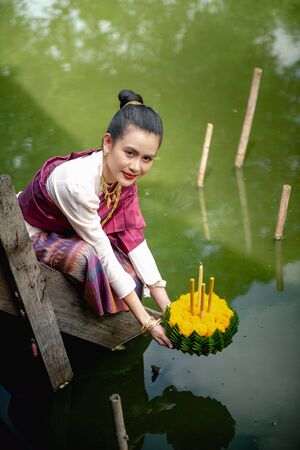 Beautiful woman ware Traditional Thai dresses hold floating basket or kratong, loy kratong festival in Thailandの写真素材