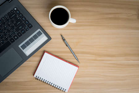Office Desk Top view Workplace With Wooden Desk, Laptop, Notepad, Pen and Dark Hot Coffee.の写真素材