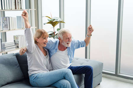Elderly senior family couple sitting in modern living room together with smile happy and romantic emotion.の写真素材