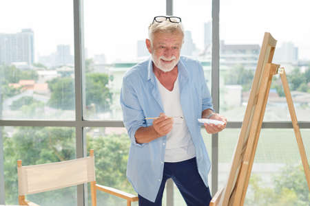 Elderly senior man in casual outfit do art paint working with happy and focus emotion in modern room.の写真素材