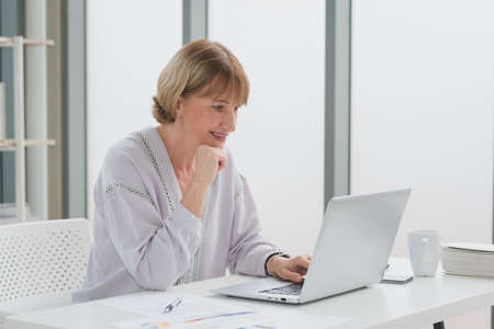 Portrait of elderly senior woman in casual outfit sitting and business working from home with smile...