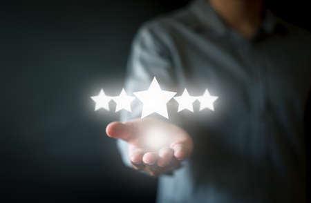 A man in formal outfit show hand in concept of rating five star symbol in dark background. Concept...