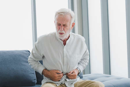 Senior elderly man in casual outfit get stomachache with unhappy and painful emotion in modern...