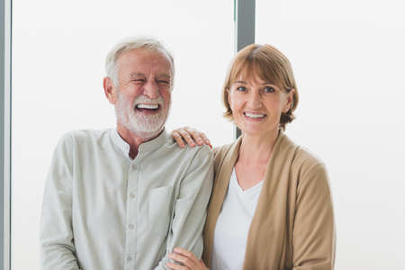 Portrait of senior elderly couple in casual outfit smiling with happiness in modern living roomの写真素材