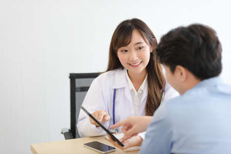 Asian doctor woman in white professional lab coat examining and diagnose the patient in modern room.の写真素材