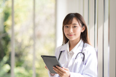 Asian doctor woman portrait in professional uniform standing with smile and confidence.の写真素材