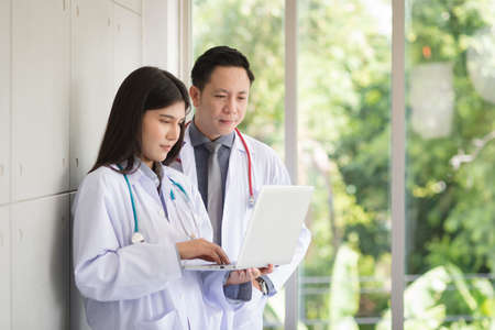 Group of Asian doctors team portrait in white lab coat professional uniform standing with colleagues in background.の写真素材