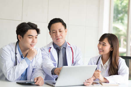 Group of Asian doctor in working uniform meeting and discuss with other colleagues in modern office clinic room.の写真素材
