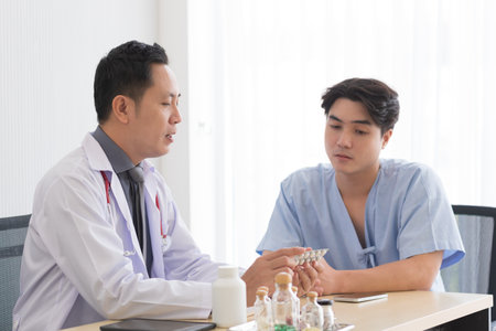 Asian doctor in professional work uniform discuss and explain symptoms to his patient.の写真素材