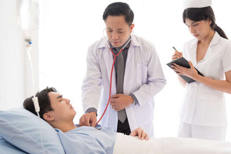 Doctor and nurse in working uniform taking care and diagnosis symptoms on the bed.の写真素材
