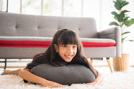 Young child girl kid lying on pillow with smile and happiness in living room.の写真素材
