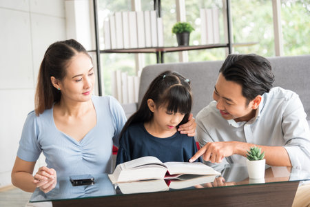 Happy family sitting together and help teaching daughter about her homework in living room.の写真素材
