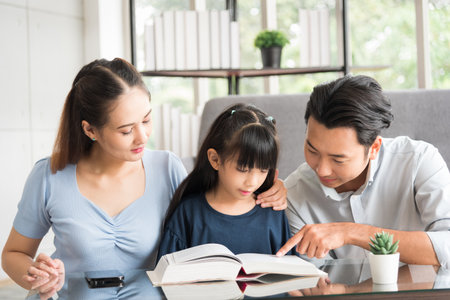 Happy family sitting together and help teaching daughter about her homework in living room.の写真素材
