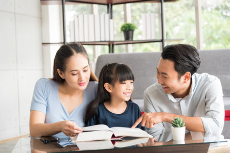 Happy family sitting together and help teaching daughter about her homework in living room.の写真素材