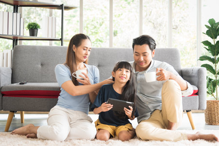 Happy parent family sitting together using tablet watching comedy with smile and laughing emotion.の写真素材
