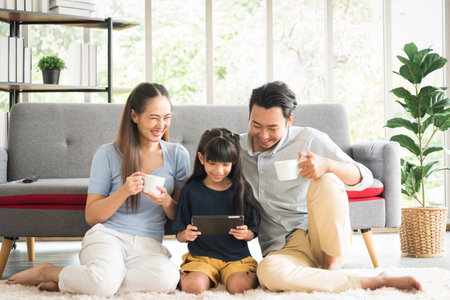Happy parent family sitting together using tablet watching comedy with smile and laughing emotion.の写真素材