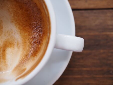 Partial top view of coffee in white cup on wood tableの写真素材