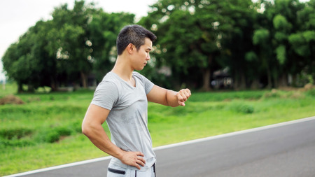 Asian man prepares for a workout at the public park, soft focus.