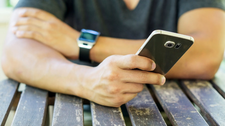 hand using a smartphone and a smartwatch.