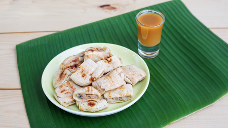 Grilled banana and sweet topping on banana leaves (Thai dessert).の写真素材