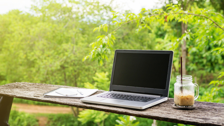 Laptop and iced latte coffee on a wooden table.の写真素材