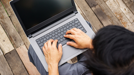 Asian man using a laptop on the balcony.の写真素材